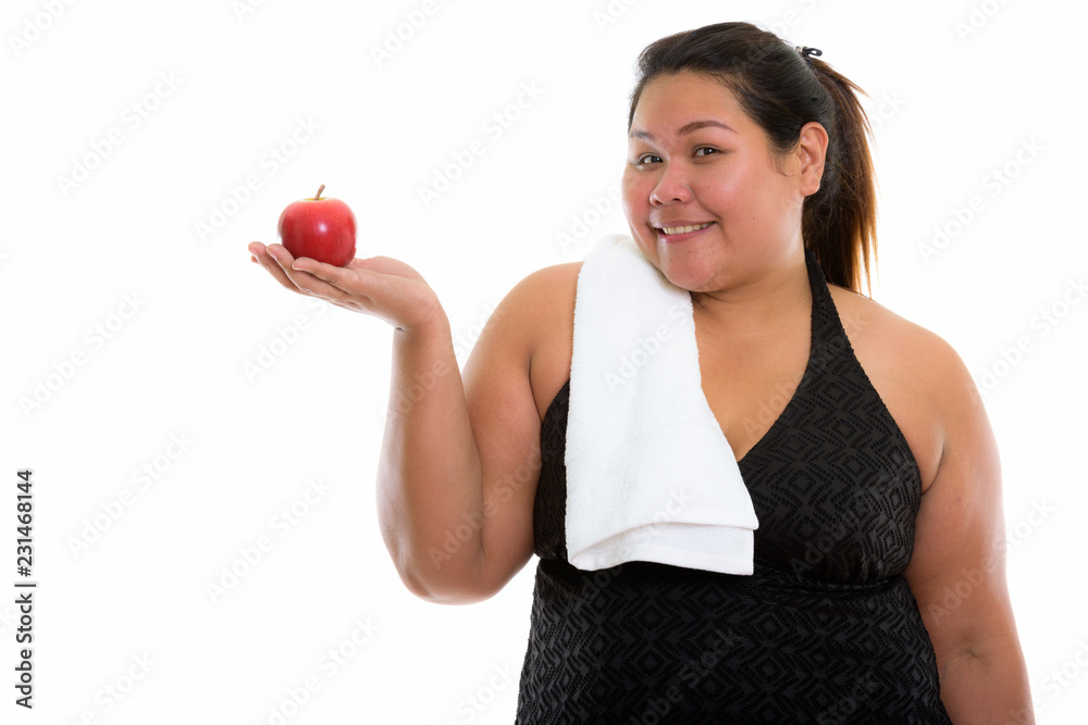 Studio shot of young happy fat Asian woman smiling and holding r Studio shot of young happy fat Asian woman smiling and holding r