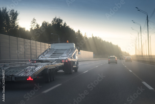 Wallpaper Mural A white car hauler truck with an empty two-tiered trailer for transporting cars is moving along the broadband scenic highway
