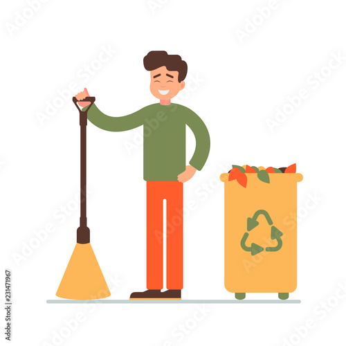 cleaner stands with a broom in his hands. happy young man collected fallen leaves in the garbage bin.  environmental concept for the community work day. 