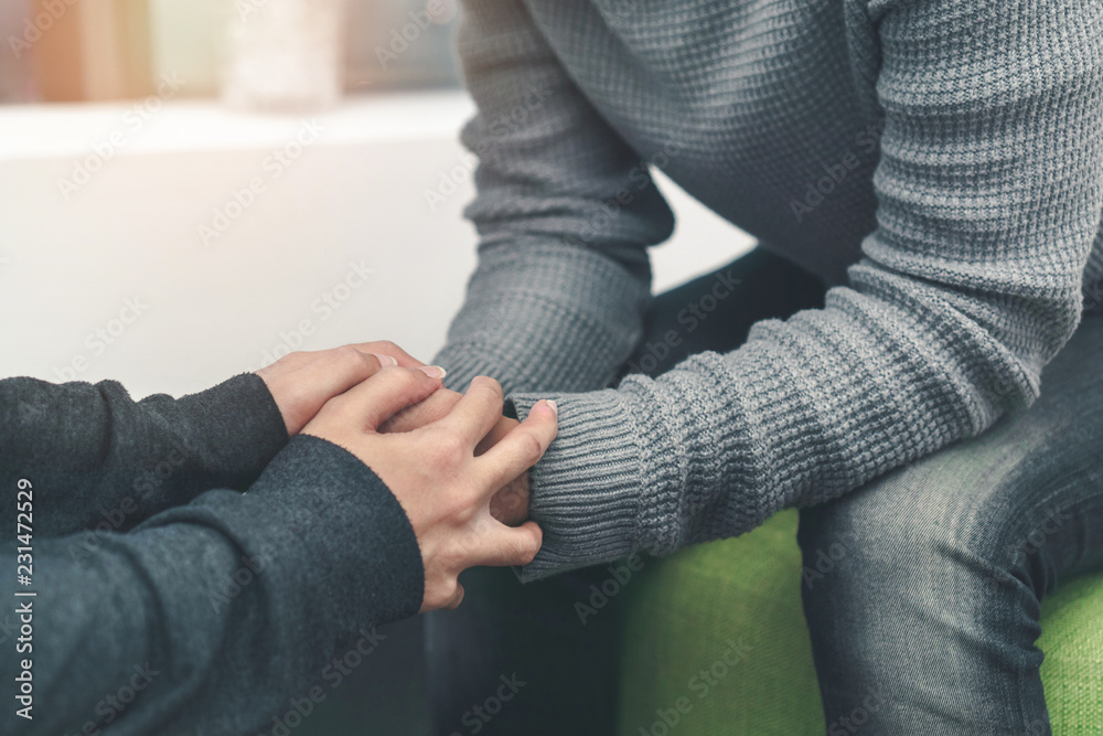 PTSD Mental health concept, Psychologist sitting and touch hand young depressed asian man for encouragement near window, Selective focus. PTSD Mental health concept, Psychologist sitting and touch hand young depressed asian man for encouragement near window, Selective focus.