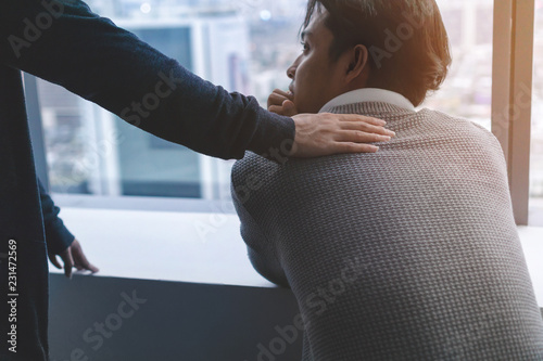 PTSD Mental health concept, Psychologist sitting and touch young depressed asian man for encouragement near window with low light environment.Selective focus.