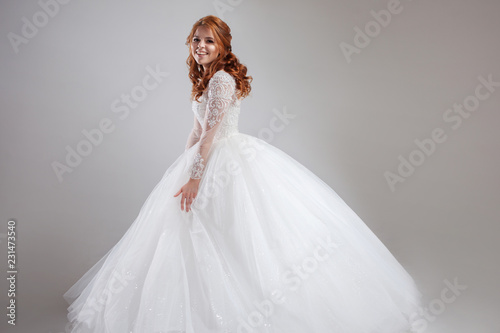 Happy laughing young woman in wedding dress. Charming bride on Light background.