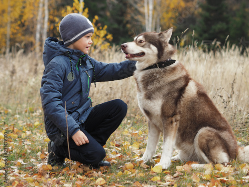 boy sit with dog in autumn park