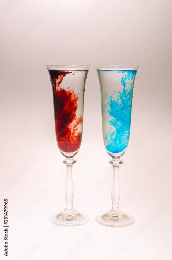 The effect of water smoke using an red and blue food coloring in two glasses for champagne on a white background. The effect of water smoke using an red and blue food coloring in two glasses for champagne on a white background.