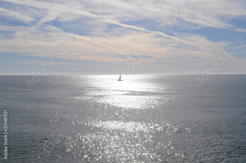 Petit voilier sur mer d'huile à l'heure du midi