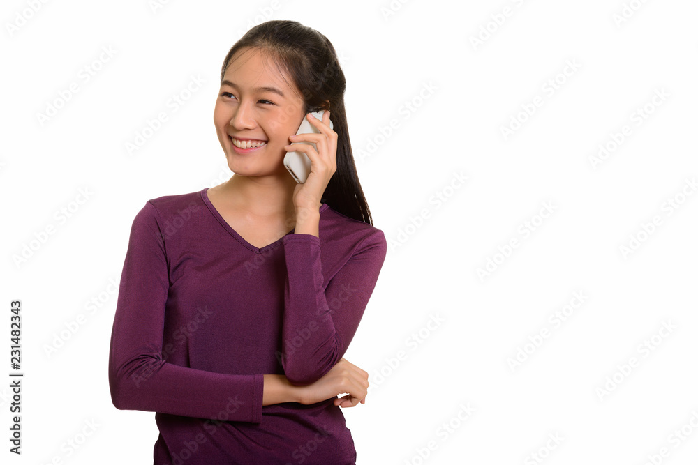 Young happy Asian teenage girl smiling and talking on mobile pho Young happy Asian teenage girl smiling and talking on mobile pho