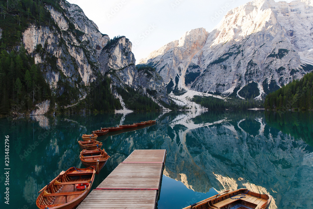 Fototapeta Beautiful landscape of Braies Lake (Lago di Braies), romantic place with wooden bridge and boats on the alpine lake, Alps Mountains, Dolomites, Italy, Europe