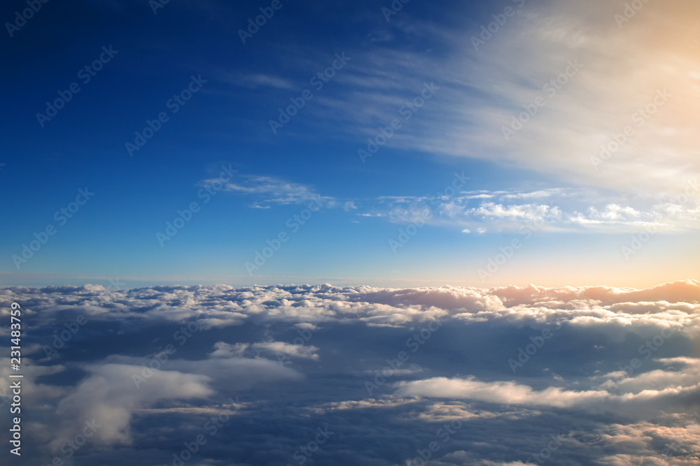 background of blue sky over cumulus clouds with the rays of the setting sun background of blue sky over cumulus clouds with the rays of the setting sun