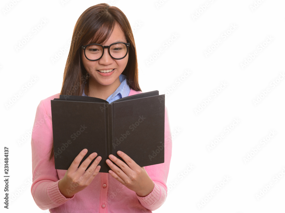 Young happy Asian teenage girl smiling and reading book Young happy Asian teenage girl smiling and reading book