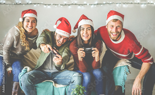 Group of happy friends having fun with video games console on christmas time photo