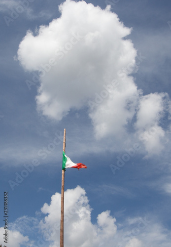 Italian flag waving against cloudy blue sky