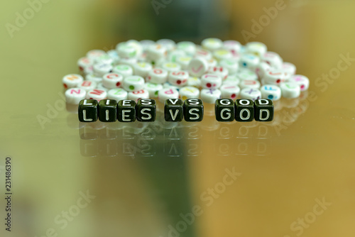 LIES VS GOD written with Acrylic Black cube with white Alphabet Beads on the Glass Background