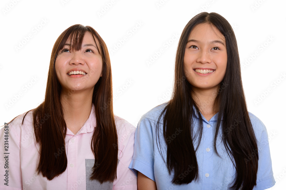 Two young happy Asian teenage girls smiling and thinking Two young happy Asian teenage girls smiling and thinking