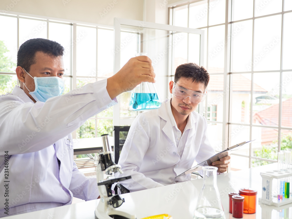 hand of the scientist show the Erlenmeyer flask the othe asian scientist looking to the erlenmeyer flask hand of the scientist show the Erlenmeyer flask the othe asian scientist looking to the erlenmeyer flask