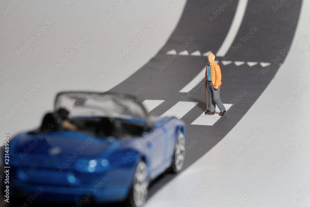 automobile e uomo anziano in miniatura che attraversa la strada sulle strisce pedonali automobile e uomo anziano in miniatura che attraversa la strada sulle strisce pedonali