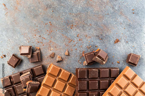 Milk and dark chocolate bars on a grey table. Top view
