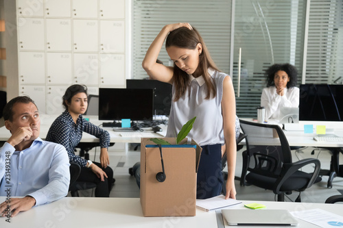 Upset female employee packing belongings in box, frustrated stressed girl getting fired from job ready to leave on last day at work, sad office worker desperate about unfair dismissal losing job