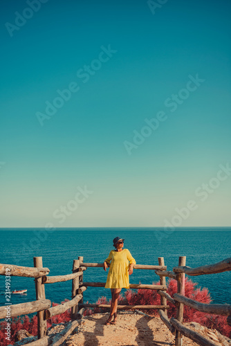 Woman standing next to wooden fence by the sea
