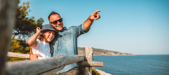 Father and daughter standing by the sea and looking into horizon