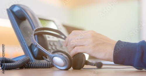 close up call center employee man hand holding headset on telephone for contact customer , support service and helpdesk concept