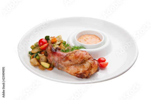 Chicken leg with baked vegetables. On a white plate