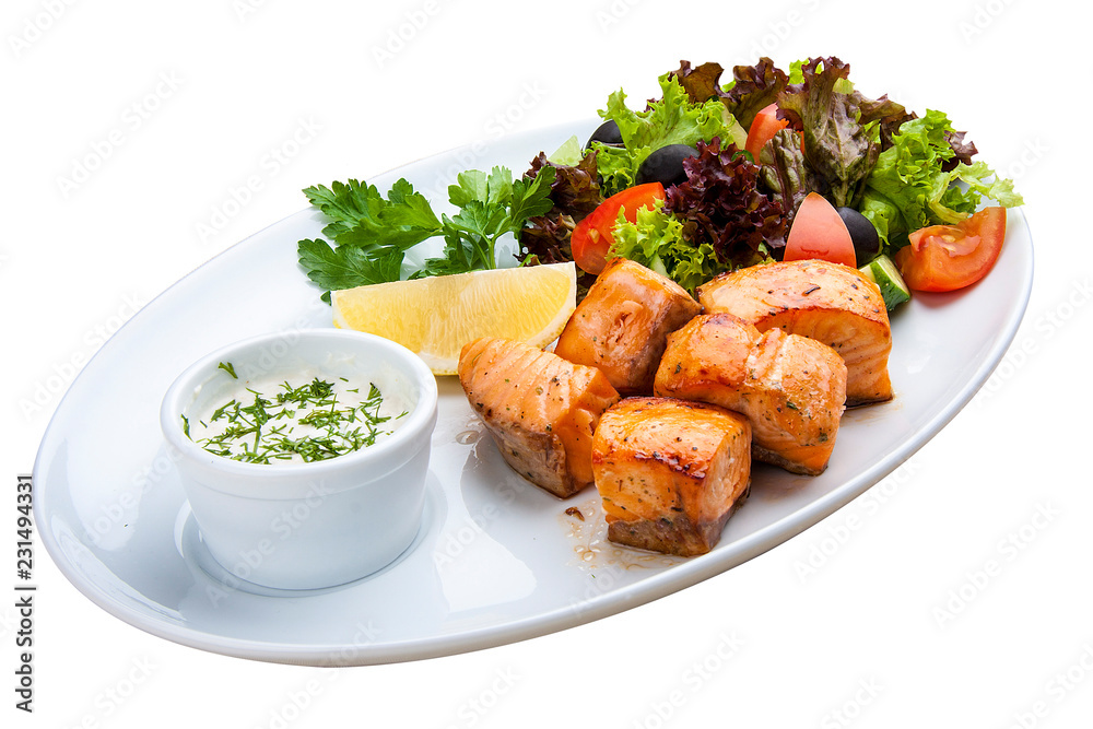 Shish kebab from salmon with vegetables and salad. On a white plate Shish kebab from salmon with vegetables and salad. On a white plate