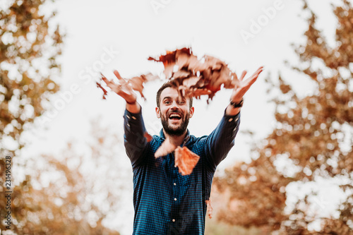 Young man throwing autumn leaves in the air