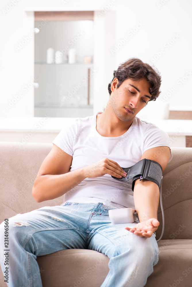 Young man measuring blood pressure at home Young man measuring blood pressure at home