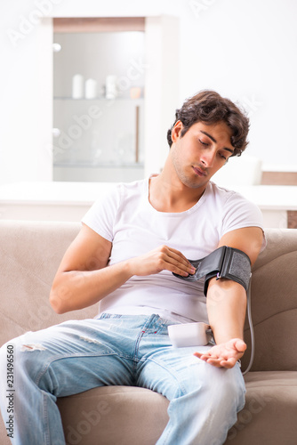 Young man measuring blood pressure at home