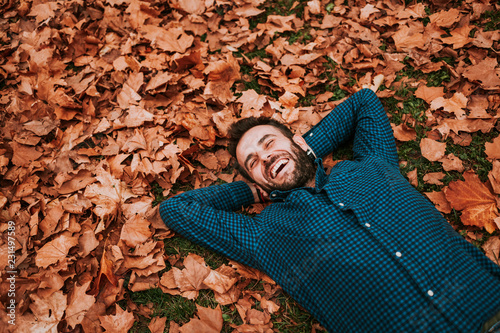 Young man lying down on the ground covered in autumn leaves