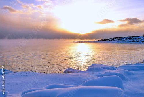 Sunset and cold fog spreads over freezing northern sea