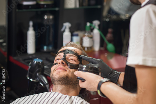 Barber putting black mask against black dots on male face