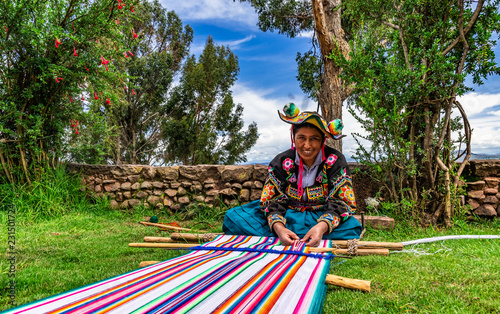 Junge Frau aus Peru beim weben von Alpakawolle für einen Wandteppich photo