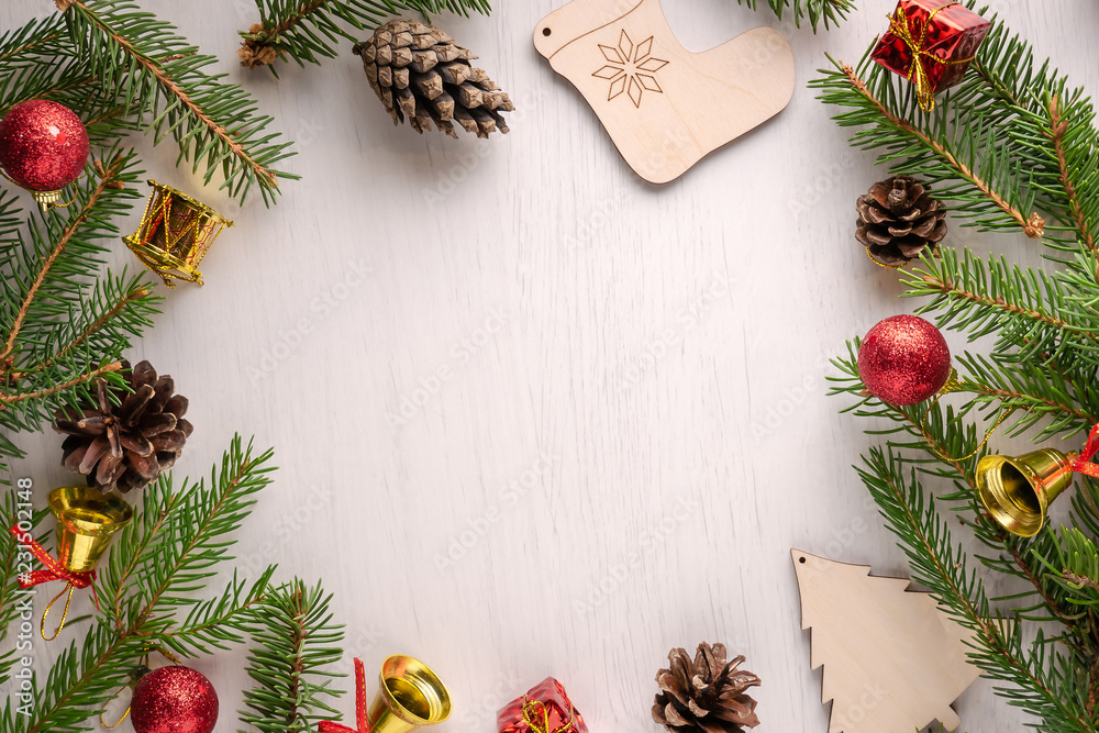 Green spruce branches, red and golden Christmas decorations and pine cones on white background with copy space