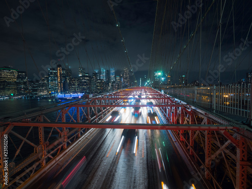 Traffic cars over the Brooklyn Bridge. Against the night cityscape NYC