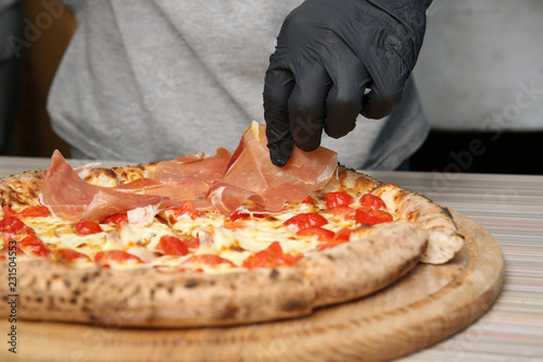 Professional chef preparing Italian oven baked pizza in restaurant, closeup