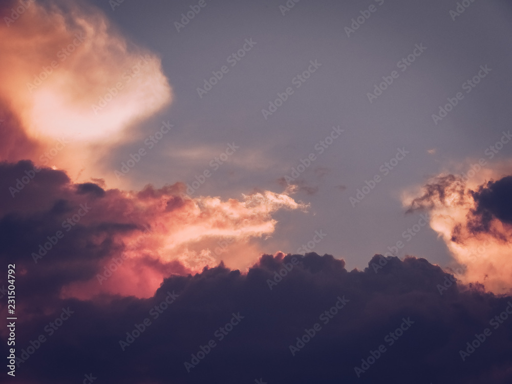 Beautiful romantic sky with pink puffy clouds during sunset.