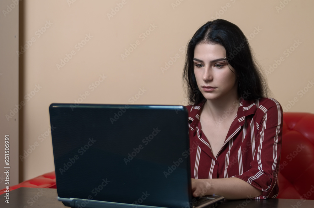 Teenager girl doing her work on laptop with neutral face Teenager girl doing her work on laptop with neutral face
