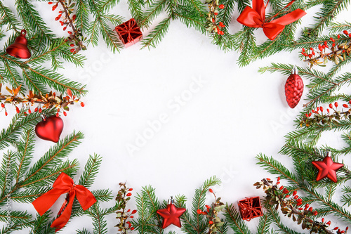 Spruce branches decorated with red ornaments and red barberry berries on a white background.