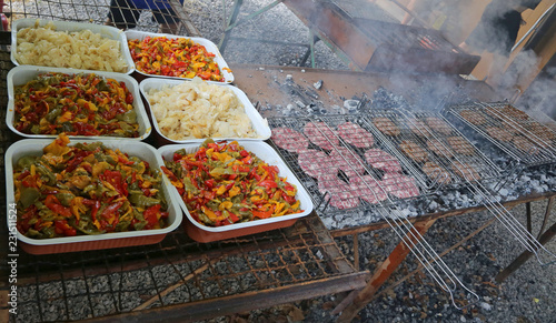 trays with onions and peppers next to grills with burgers photo