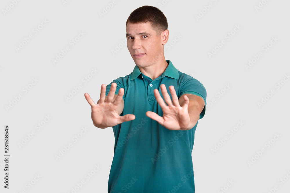 Waist up shot of handsome man demonstrates refusal gesture, asks not bother him, rejects something, has displeased facial expression, dressed in casual clothes, isolated over white studio wall Waist up shot of handsome man demonstrates refusal gesture, asks not bother him, rejects something, has displeased facial expression, dressed in casual clothes, isolated over white studio wall