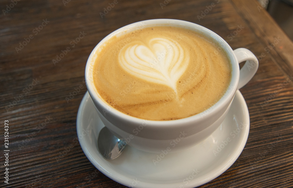 A cup of coffee with a pattern in the form of a heart on the milk foam. The big cup of cappuccino with latteart. Drawing on milk foam in the form of a heart. A cup of coffee with a pattern in the form of a heart on the milk foam. The big cup of cappuccino with latteart. Drawing on milk foam in the form of a heart.