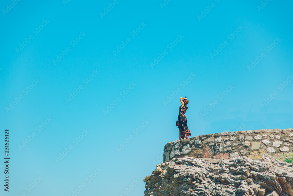woman stand on the cliff in light dress at sunny day