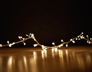 Christmas golden  lights on black  background. Xmas  garland on wooden floor, copyspace