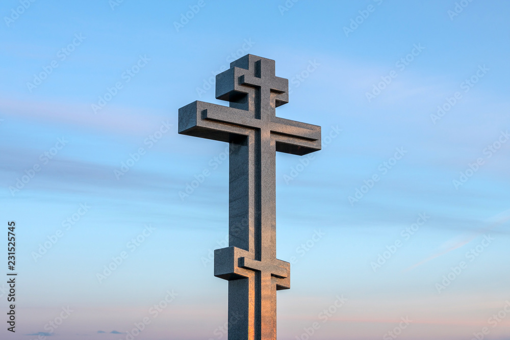 stone christian cross on blue sky