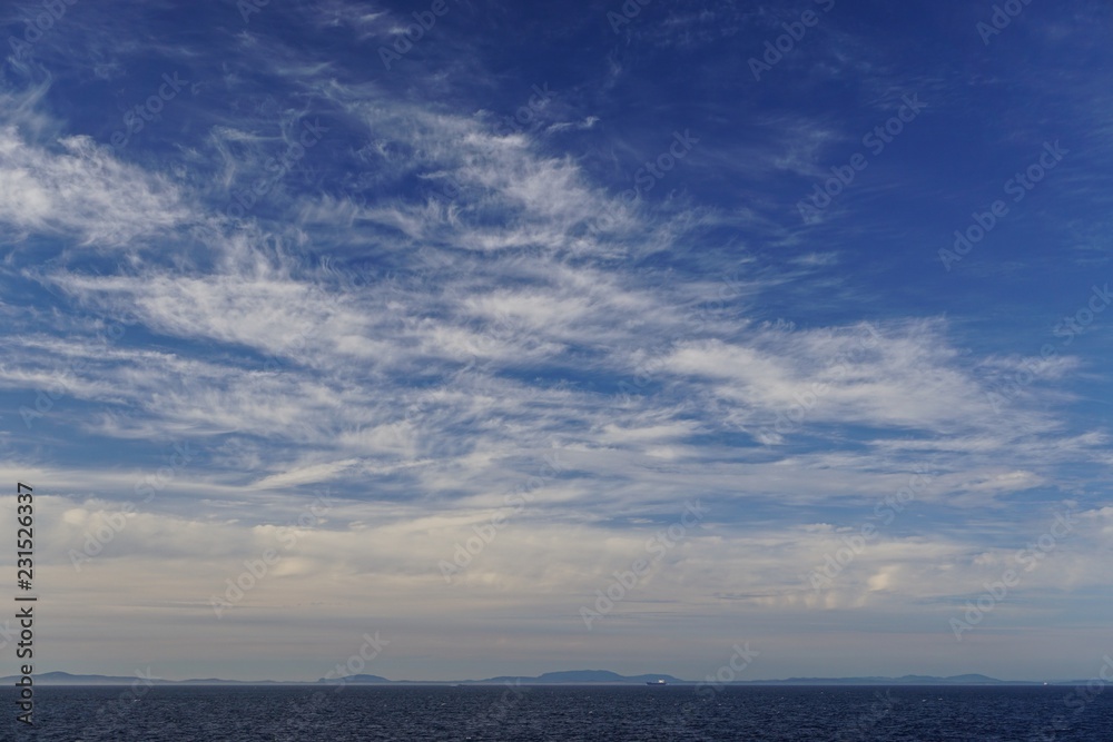 View from a cruise ship of feathery clouds over the North Pacific Ocean, mountains of the Pacific Northwest and ships in the distance. View from a cruise ship of feathery clouds over the North Pacific Ocean, mountains of the Pacific Northwest and ships in the distance.