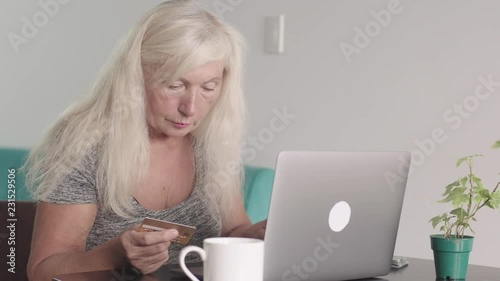 Close up shot of retired old woman ( grandmother ) using laptop at home in the living room. Elderly woman doing shopping online and pay bill by credit bank card using her modern PC. Online purchase