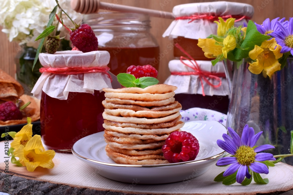 Stack of pancakes decorated with raspberry and mint on a white plate. Village style