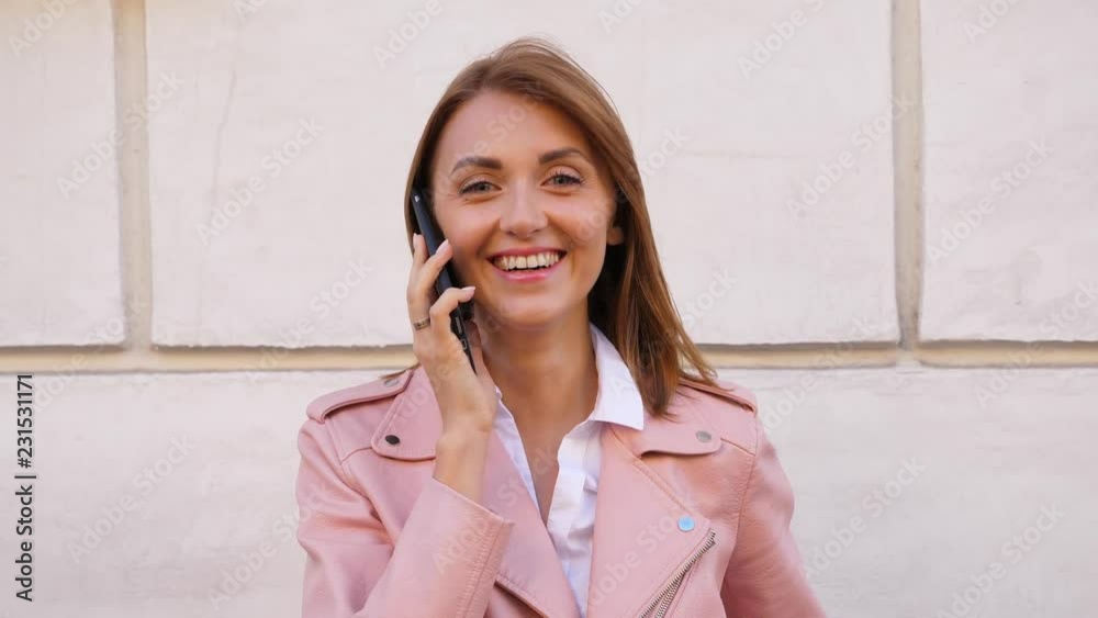 Happy laughing woman talking on mobile phone and looking in camera Happy laughing woman talking on mobile phone and looking in camera