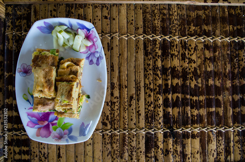 MARTABAK TELUR - stuffed pancake or pan-fried bread Indo-style on a plate, copy-space right. photo